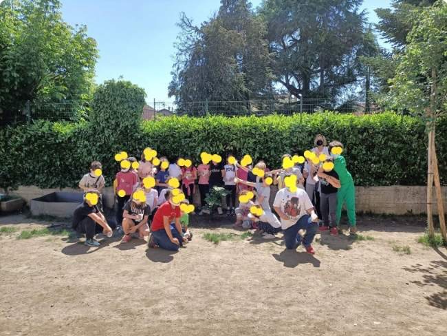 Bambini del doposcuola di Pollenzo seduti all’aperto dopo aver piantato un albero con la Comunità